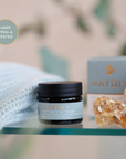 Maydi+ peptide eye cream jar on a table with a blurred background