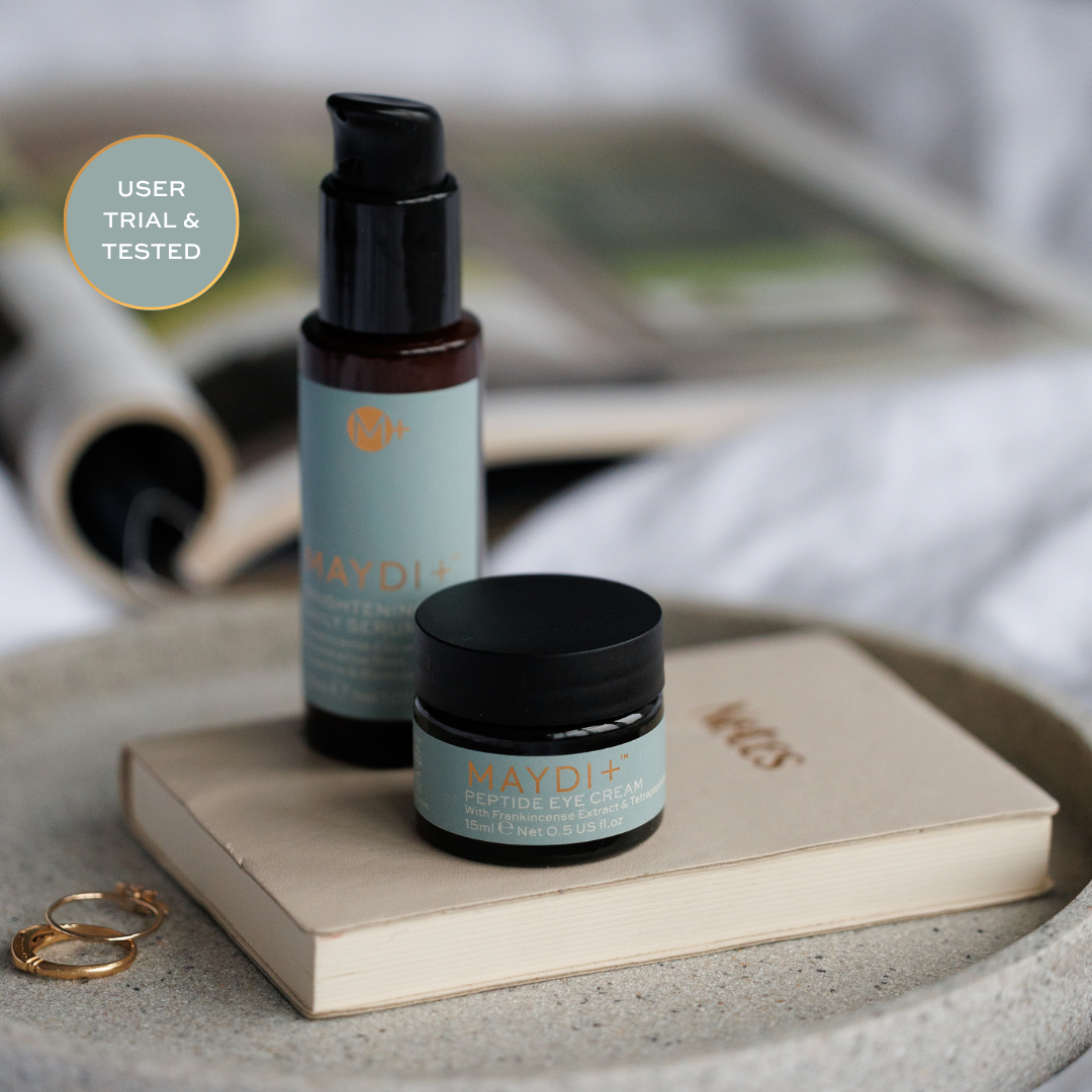 Two skincare products( brightening serum & Peptide Eye Cream) on a book with a blurred background