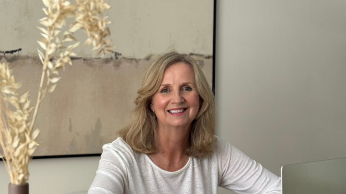woman in white top sitting at desk managing a skincare brand